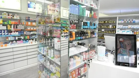 Unutrašnjost moderne ljekarne s nizom polica ispunjenih lijekovima i kozmetikom.