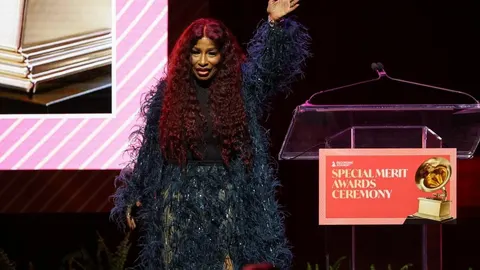 Chaka Khan s crvenom kosom i u perjanom ogrtaču maše na pozornici.