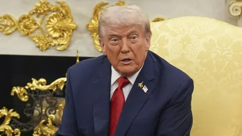 Donald Trump u odijelu s crvenom kravatom govori tijekom sastanka