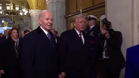 Joe Biden i Donald Trump prolaze kroz svečanu dvoranu u pratnji osiguranja.