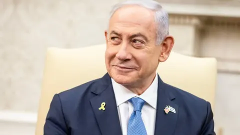 Benjamin Netanyahu u tamnom odijelu s plavom kravatom gleda u stranu.