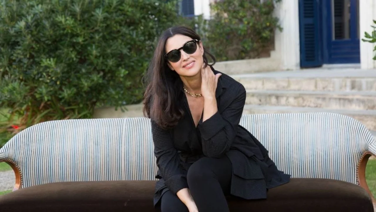 Monica Bellucci sjedi na kauču u crnoj odjeći s naočalama