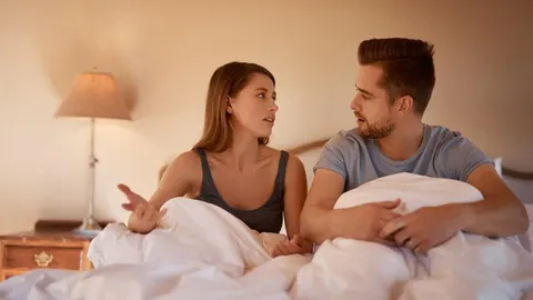 Mladi par u krevetu razgovara o intimnim problemima i nelagodi u spavaćoj sobi.