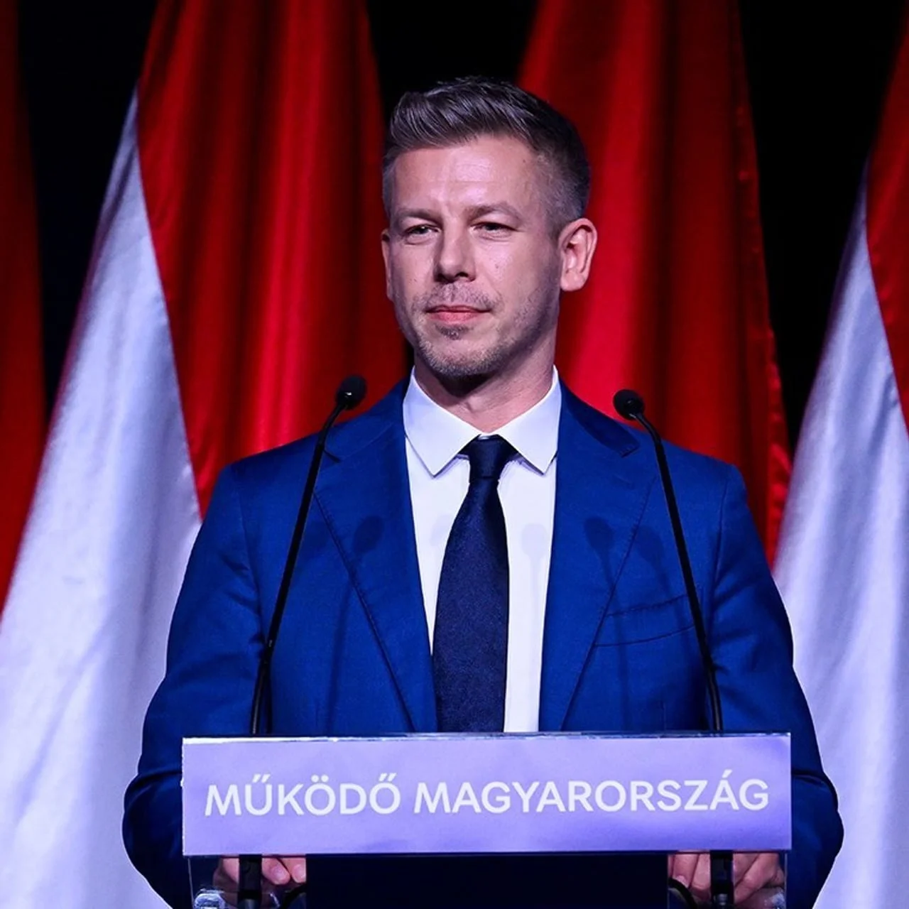Peter Magyar drži govor za govornicom s mađarskim zastavama u pozadini