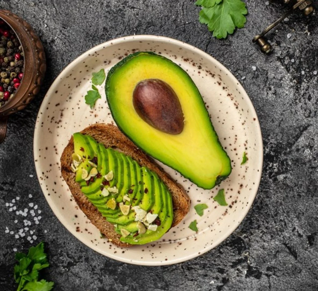 Polovica svježeg avokada i tost s namazom na tanjuru