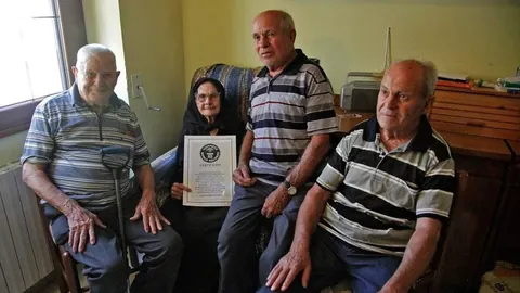 Četvero starijih osoba sjedi u sobi i pokazuje Guinnessov certifikat.