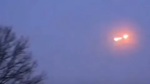 Svijetleći meteorit na noćnom nebu iznad krošnji drveća