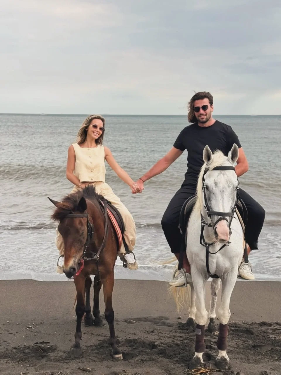 Maja Šuput i Šime Elez jašu konje na pješčanoj plaži dok se drže za ruke.