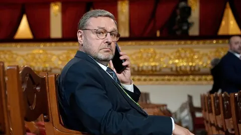 Konstantin Kosačev s naočalama razgovara na mobitel u svečanoj dvorani.