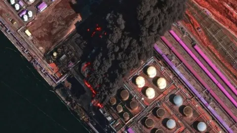 Satelitska snimka požara i crnog dima iznad naftnog terminala u luci.