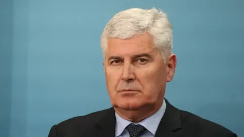 Portret Dragana Čovića u tamnom odijelu ispred plave pozadine