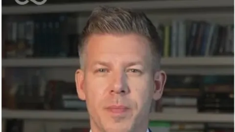 Portret Pétera Magyara ispred police s knjigama