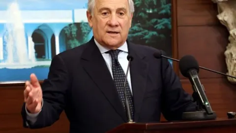 Antonio Tajani u tamnom odijelu govori za govornicom s mikrofonima.