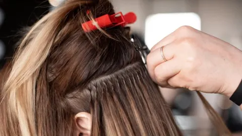 Postupak umetanja ekstenzija na pramenove prirodne kose u frizerskom salonu.