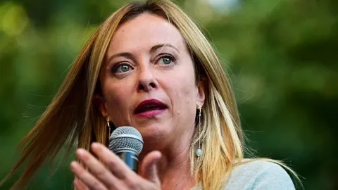 Krupni kadar talijanske premijerke Giorgie Meloni dok govori u mikrofon na otvorenom.