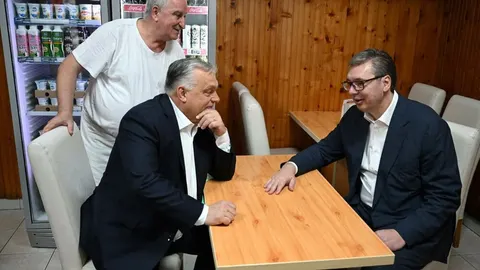 Aleksandar Vučić i Viktor Orban razgovaraju za drvenim stolom u restoranu.