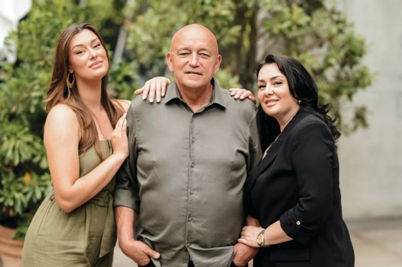 Željko Krušlin Kruška u maslinastoj košulji stoji između dvije žene na otvorenom.