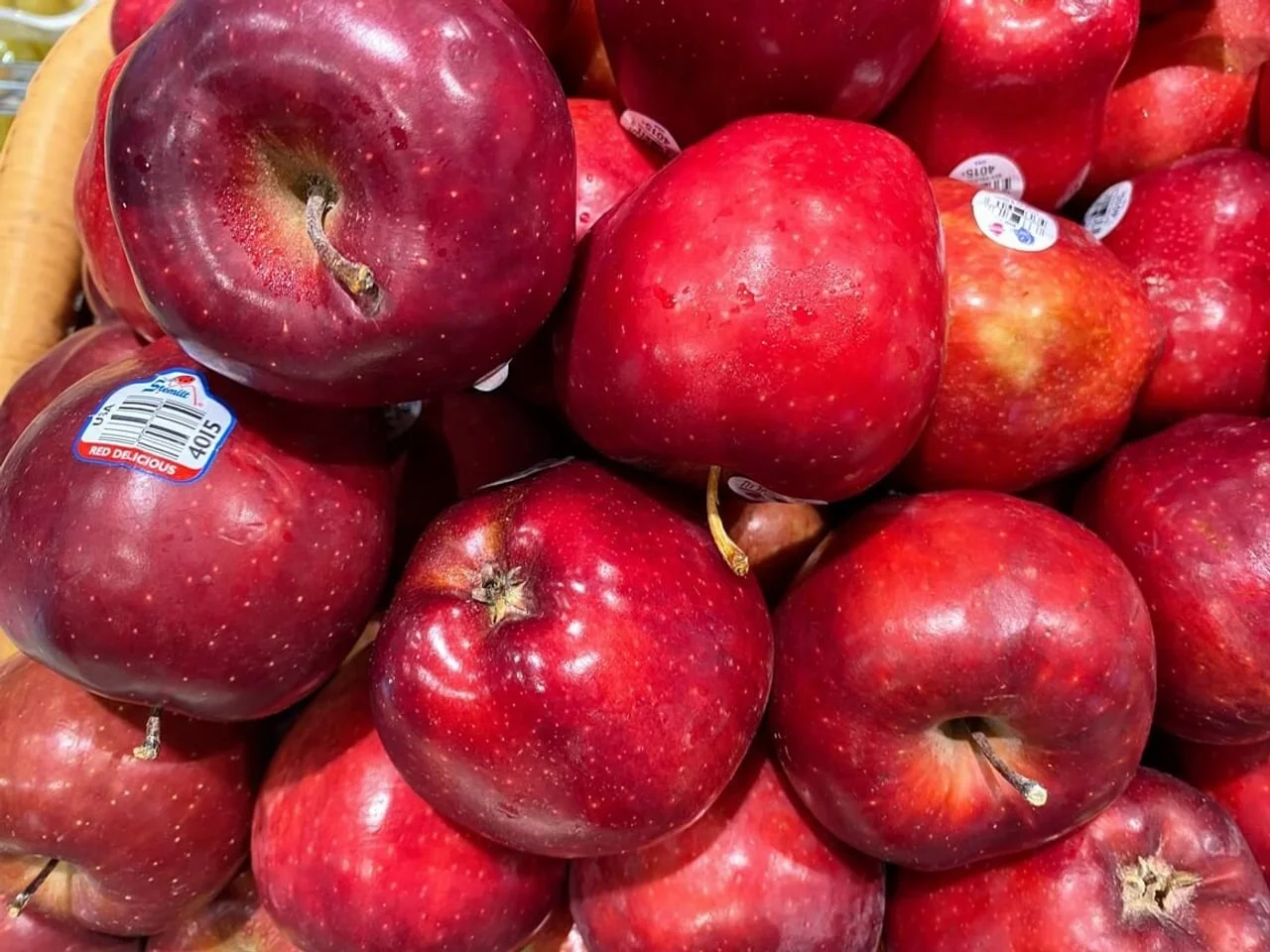 Hrpa crvenih jabuka u košari s vidljivim bijelim naljepnicama