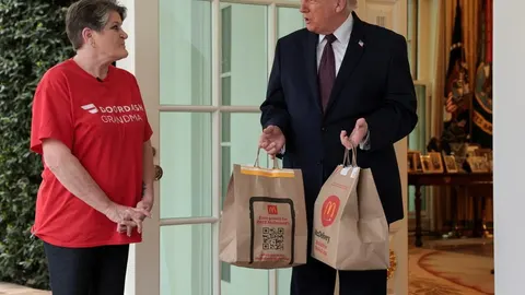 Donald Trump preuzima vrećice s hranom od dostavljačice ispred Bijele kuće.