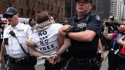 Dva policajca NYPD-a uhićuju prosvjednika u majici s natpisom Free Palestine.