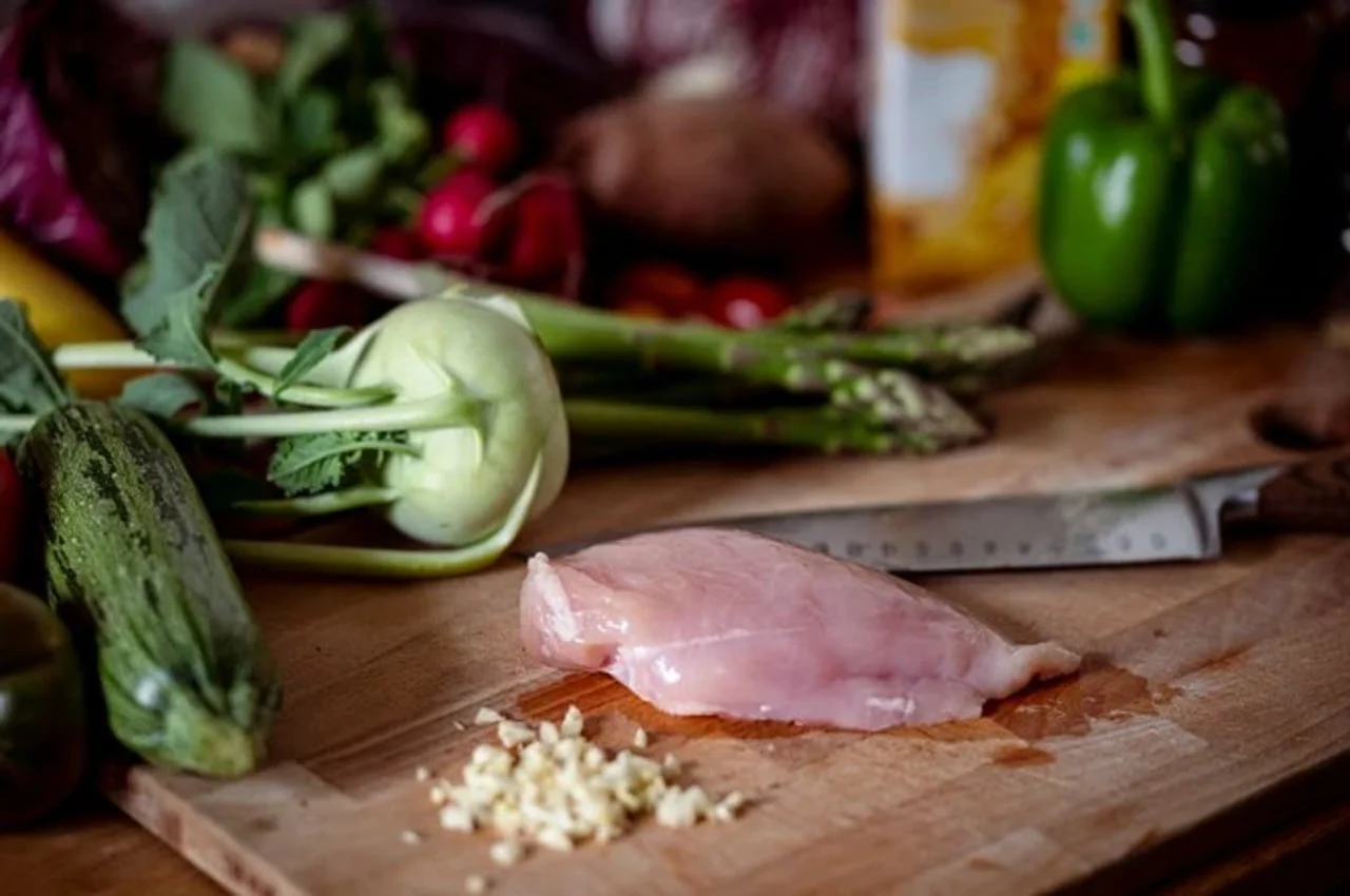 Sirova piletina na drvenoj dasci uz povrće i nož