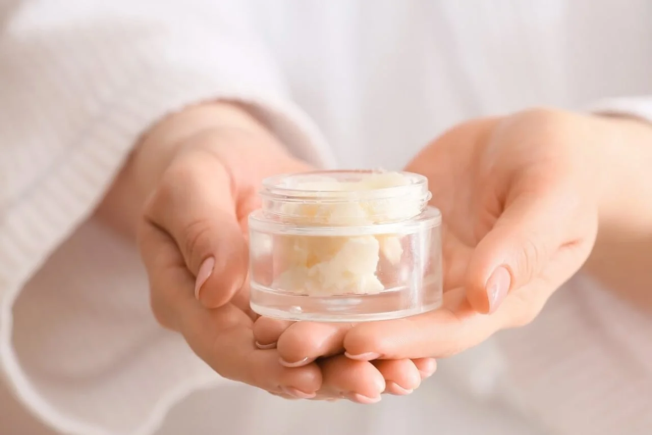 Ruke drže malu staklenku s bogatim prirodnim maslacem za tijelo.