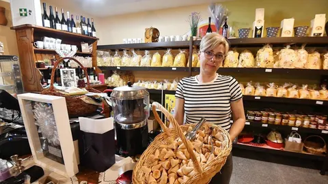 Žena stoji u trgovini domaćih proizvoda s košarom punom peciva.