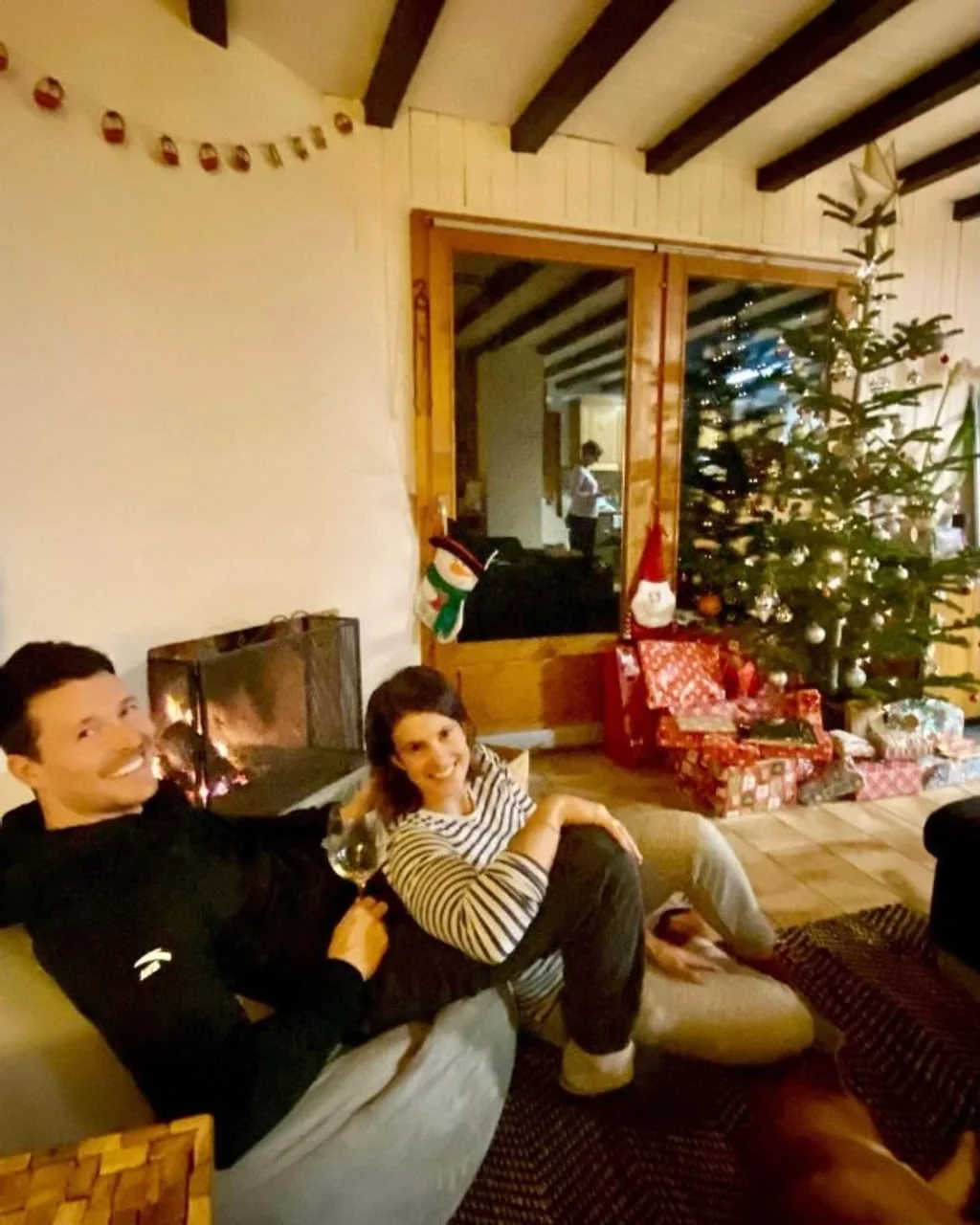 Par sjedi na podu ispred kamina i božićnog drvca