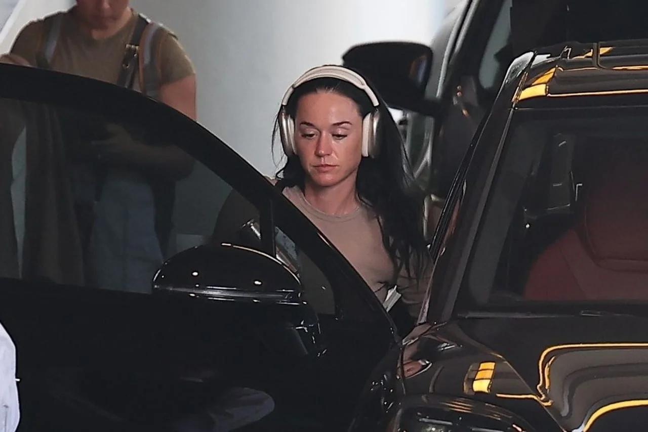 Katy Perry s bijelim slušalicama izlazi iz crnog automobila.
