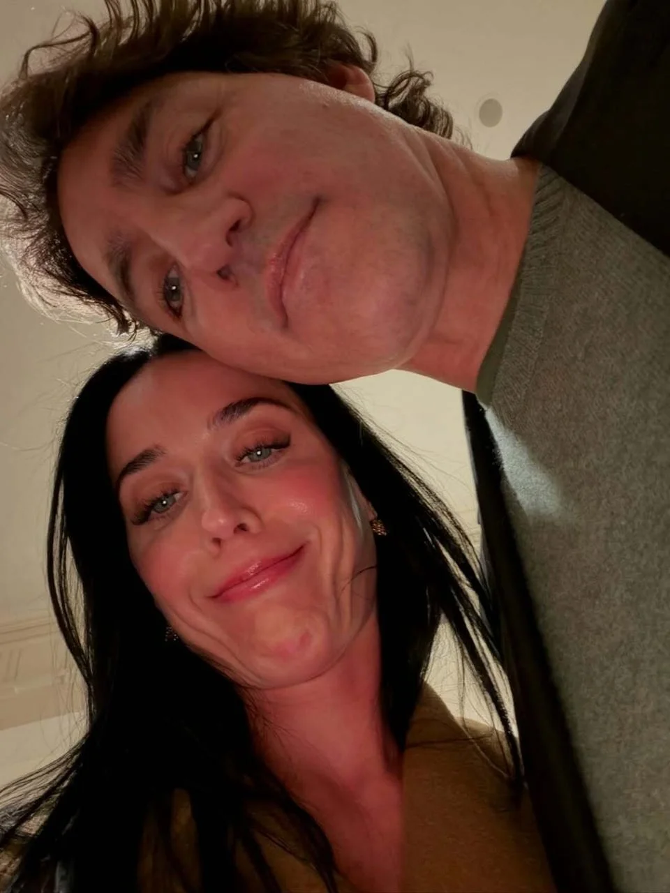 Kratki krupni plan selfija dvoje ljudi koji se smiješe prema kameri odozdo.