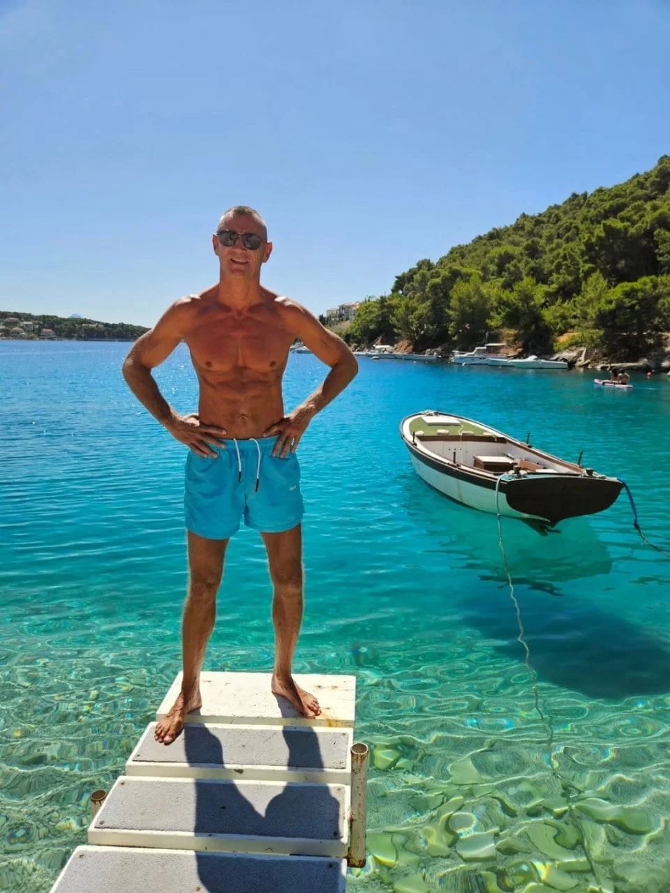 Stipe Drviš pozira bez majice na drvenom molu uz tirkizno more