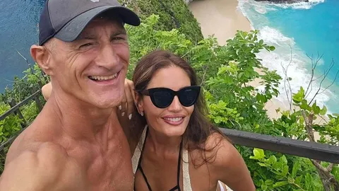 Stipe Drviš i nasmijana žena s tamnim naočalama na obali mora