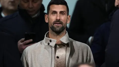 Novak Đoković u bež jakni gleda prema naprijed s ozbiljnim izrazom lica