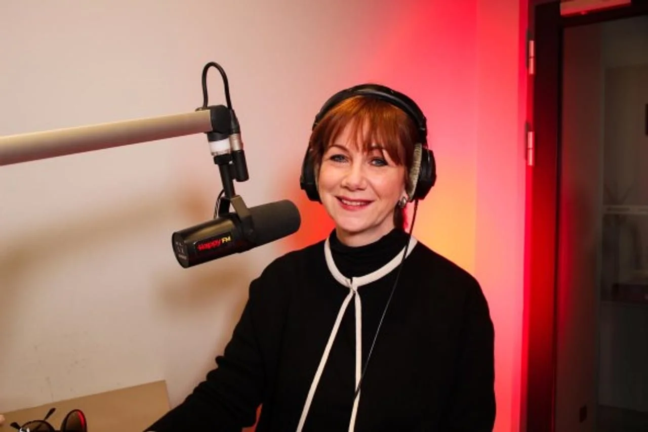 Nasmijana Maja Blagdan sa slušalicama u radijskom studiju ispred mikrofona.