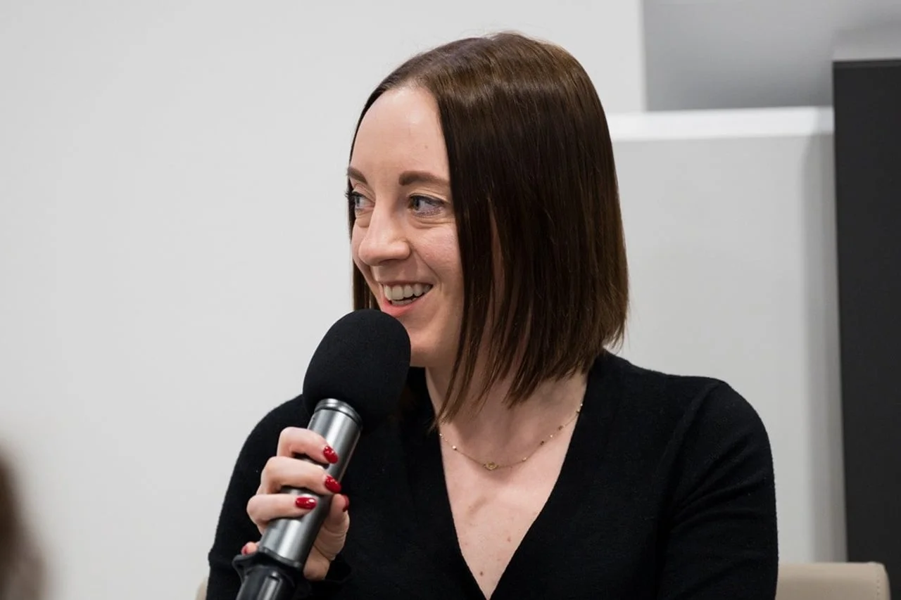 Mlađa žena s tamnom kosom nasmijano govori u mikrofon tijekom panela.