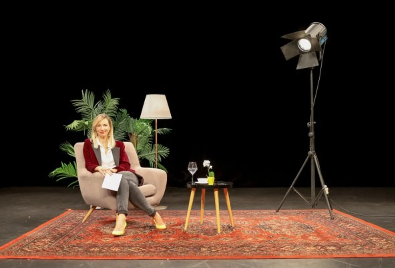 Široki kadar studija s Jelenom Makovičić, rasvjetom i malim stolićem.