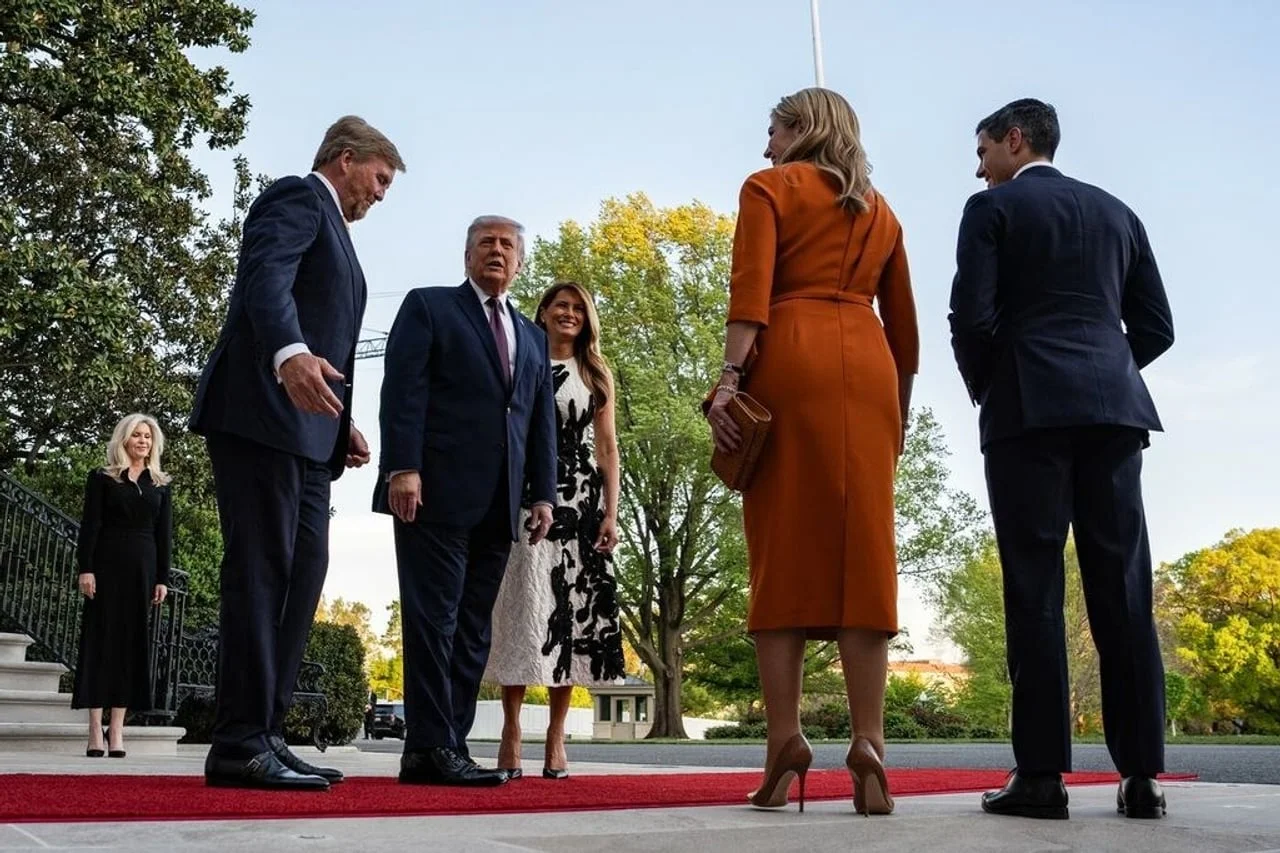 Kralj Willem-Alexander i Donald Trump u razgovoru na crvenom tepihu ispred zgrade.