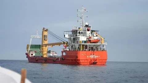 Veliki crveni teretni brod Al Mabroukah 2 plovi otvorenim morem pod vedrim nebom.