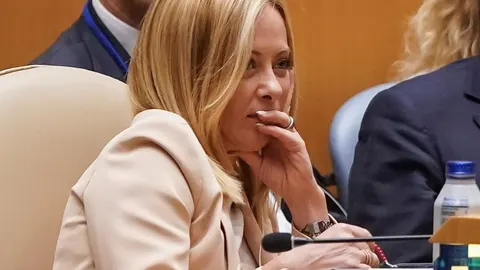 Giorgia Meloni sjedi s rukom na licu tijekom službenog sastanka.