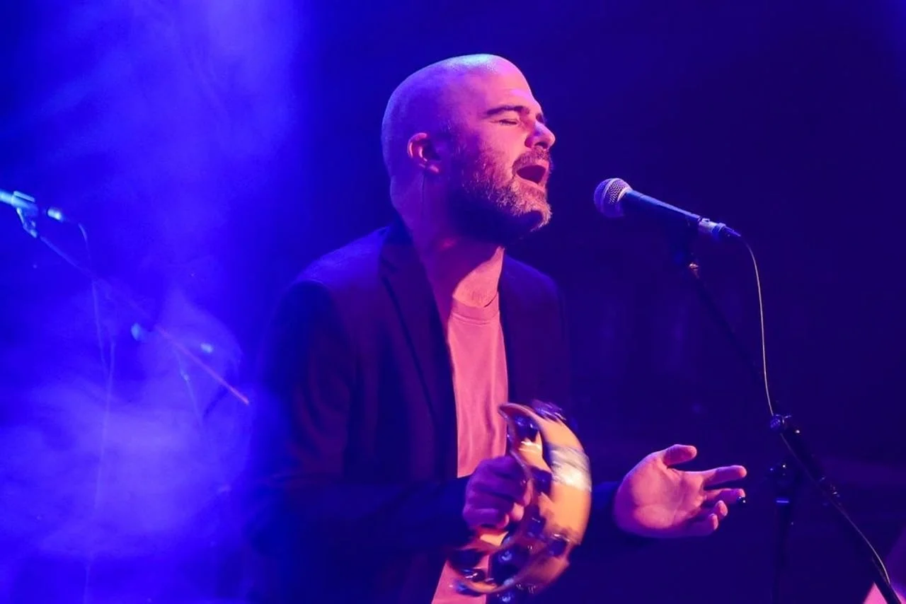 Filip Riđički pjeva u mikrofon i drži def pod plavim svjetlima.