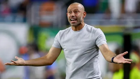 Javier Mascherano u sivoj majici s raširenim rukama na nogometnom stadionu.