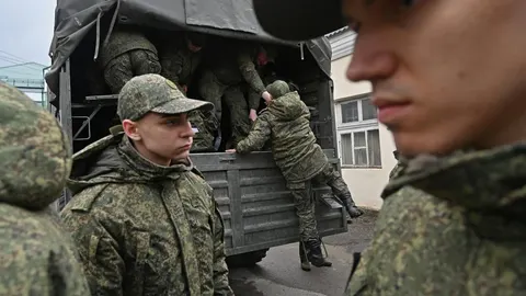 Mladi ruski vojnici u maskirnim uniformama ulaze u vojni kamion.