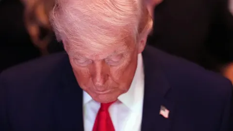 Donald Trump snimljen izbliza s pognutom glavom i ozbiljnim izrazom lica