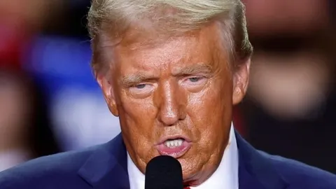 Krupni kadar lica Donalda Trumpa dok govori u mikrofon na javnom događaju.