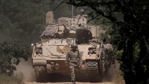 Vojno oklopno vozilo na prašnjavom putu s vojnikom ispred