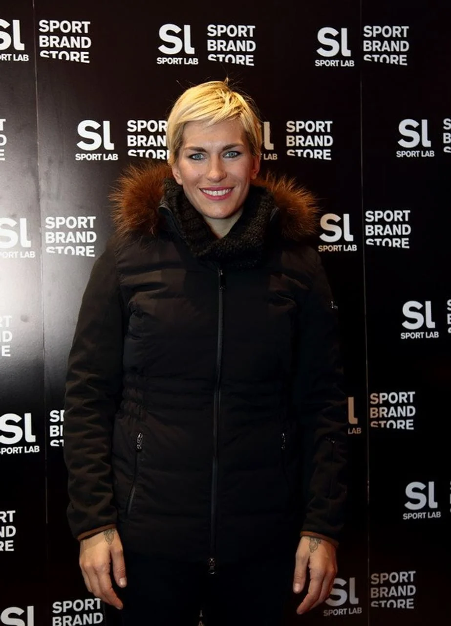 Nika Fleiss u toploj zimskoj jakni nasmijana pozira ispred crnog zida.