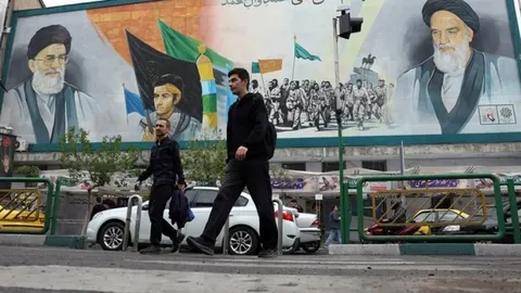 Prolaznici ispred velikog murala s vjerskim vođama Irana u Teheranu.