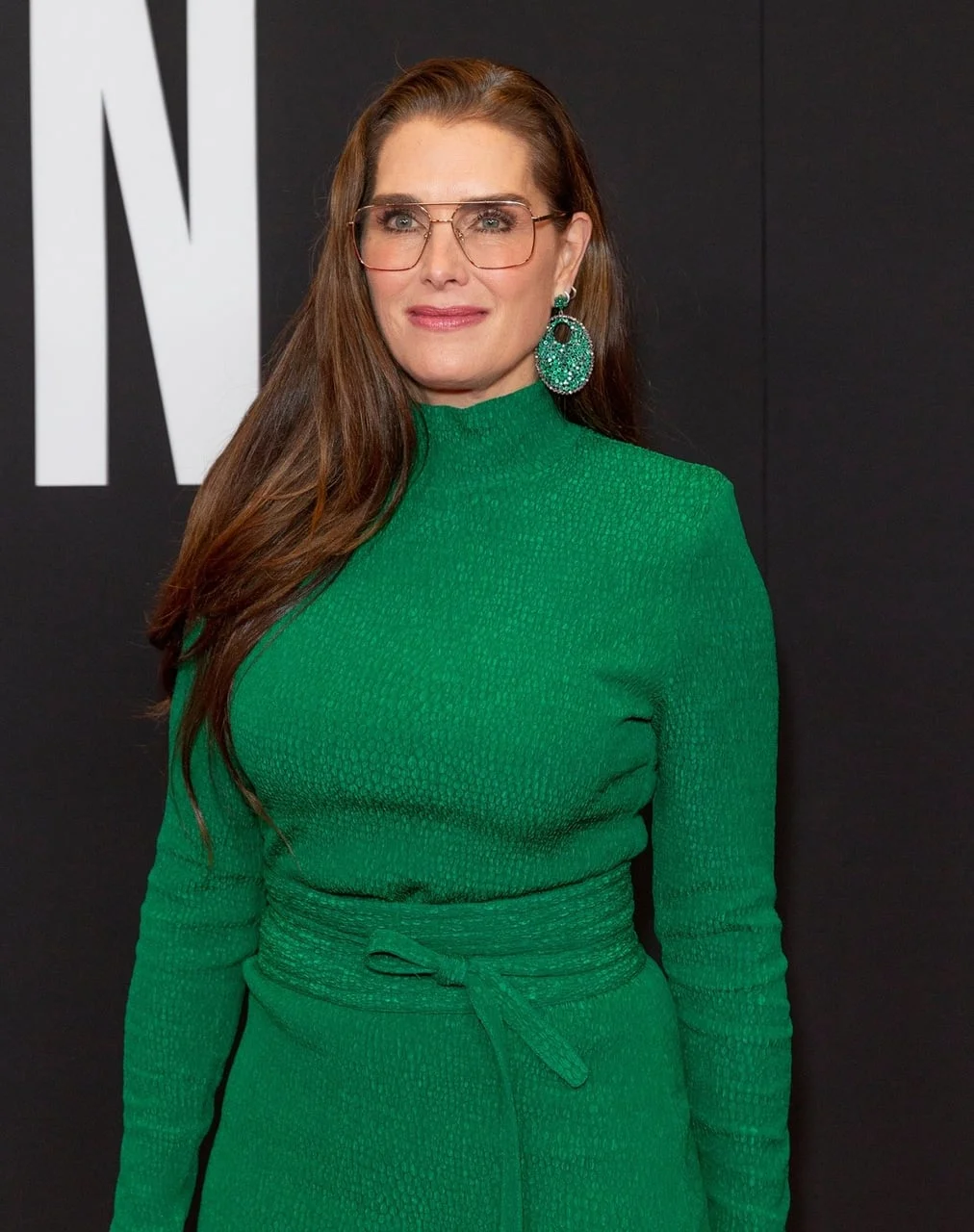 Brooke Shields u zelenoj haljini s naočalama na crvenom tepihu.