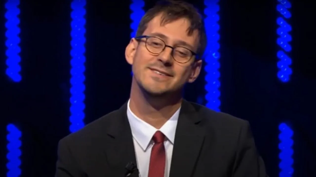 Lovac Krešimir Sučević Međeral u tamnom odijelu s crvenom kravatom ispred plavih svjetala.