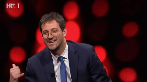 Krešimir Sučević Međeral nasmijan u studiju kviza Potjera s crvenom pozadinom.